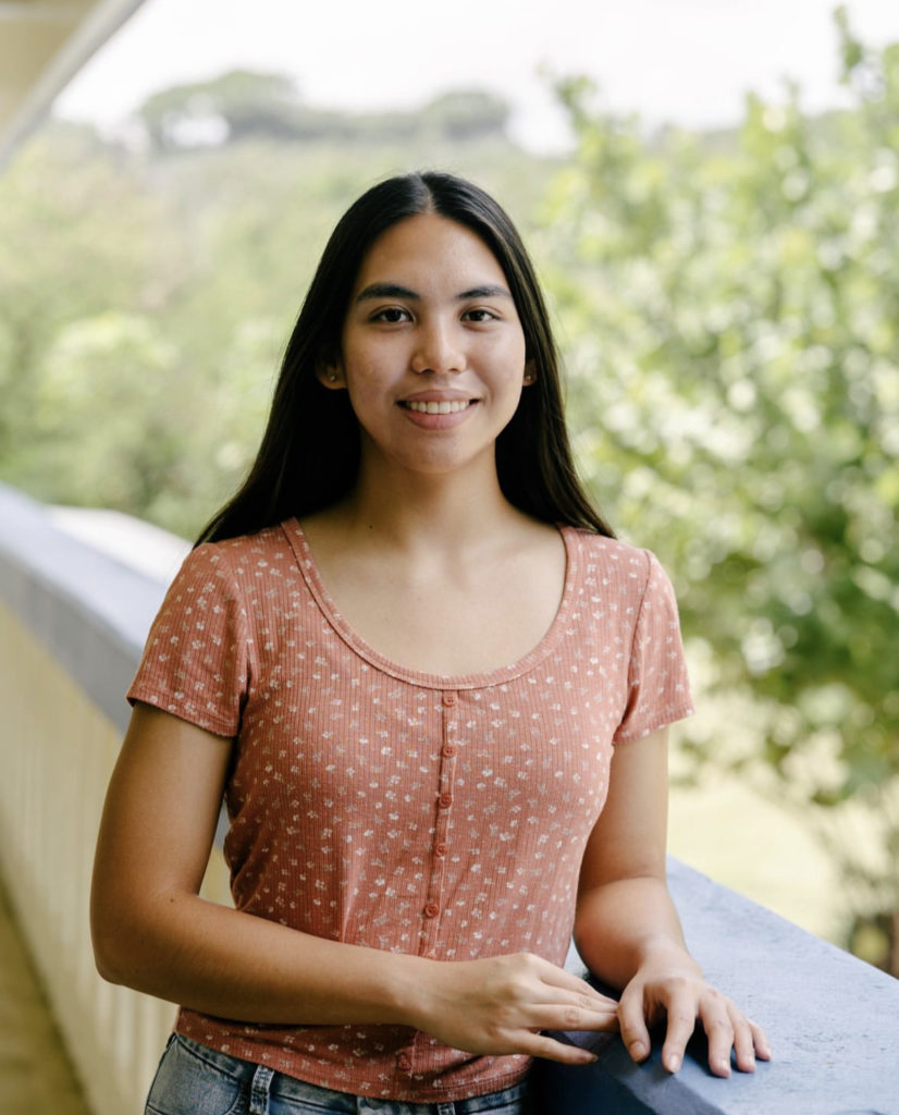 A smiling student poses for a picture on an outdoor balcony