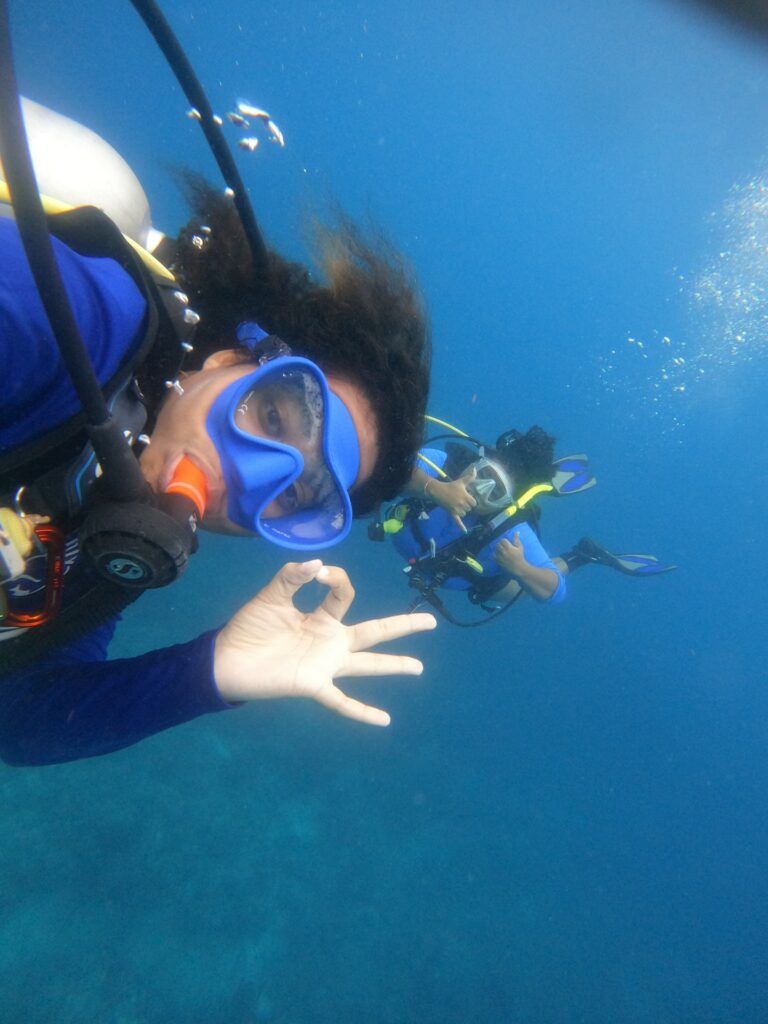 A young scuba diver gives the "OK" sign underwater