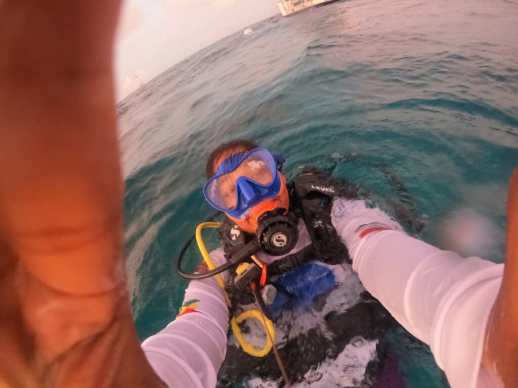 A young woman in scuba diving gear poses for a selfie in the water